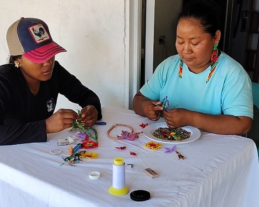 Artesana indígena del Amazonas colombiano tejiendo aretes de mostacilla hechos a mano con diseño de flores y colores tradicionales