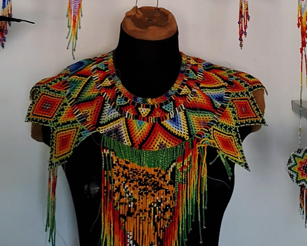 Artesana indígena del Amazonas colombiano tejiendo aretes de mostacilla hechos a mano con diseño de flores y colores tradicionales